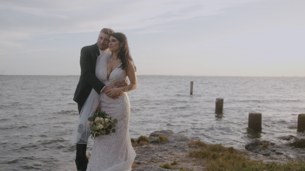 Bride and groom in front of water hugging